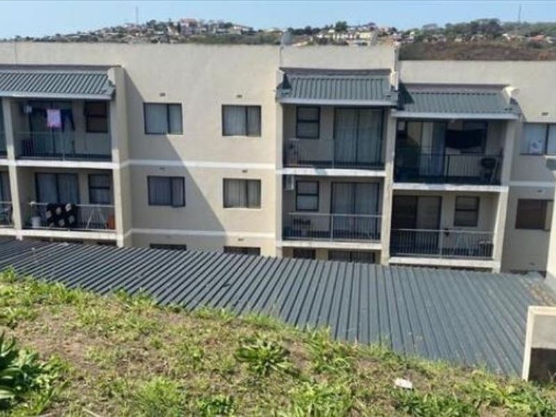 Rear elevation of a multi-story apartment complex featuring private balconies with metal railings and sliding glass doors.