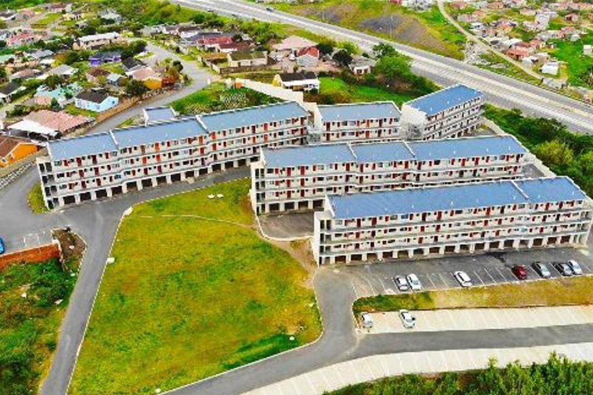 Aerial view of a multi-story apartment complex featuring paved parking areas and surrounding residential neighborhood infrastructure.