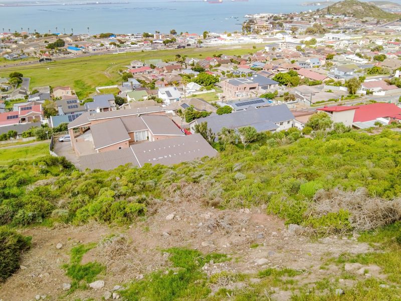 An elevated aerial view of a sloped residential plot overlooking the surrounding neighborhood and coastal bay area.