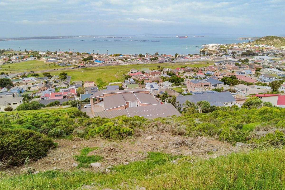 An elevated aerial view overlooking a residential neighborhood with coastal and bay views in the distance.