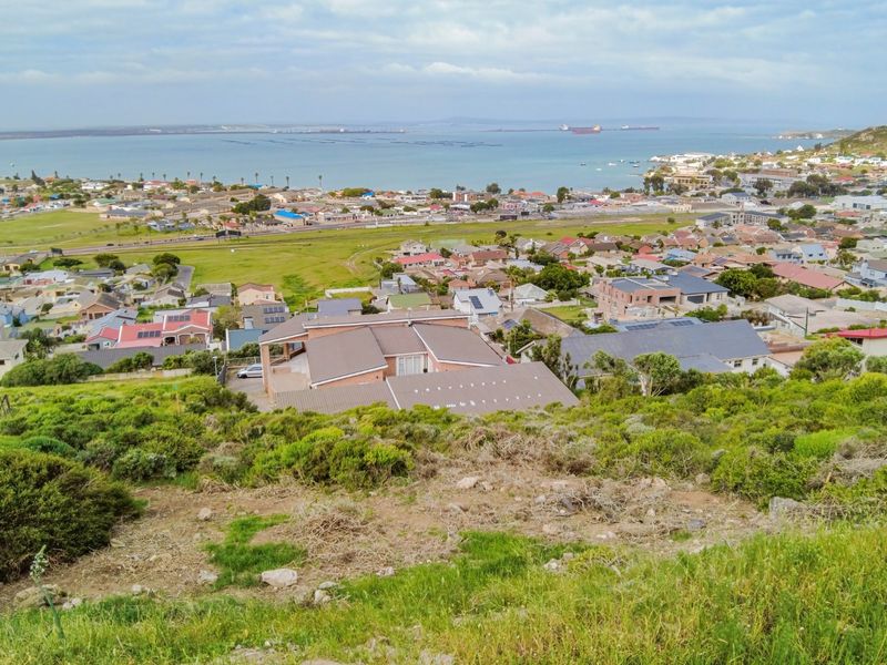 An elevated aerial view overlooking a residential neighborhood with coastal and bay views in the distance.