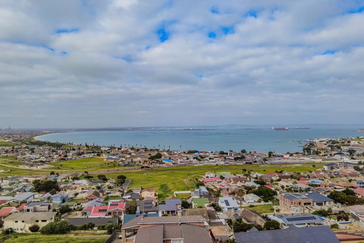 An elevated aerial view showcasing the surrounding residential neighborhood, coastal landscape, and bay area.