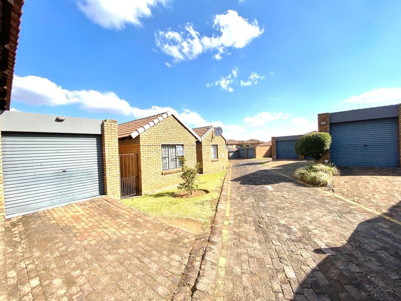 Front view of a face brick residential property featuring a paved driveway and multiple roller shutter garage doors.