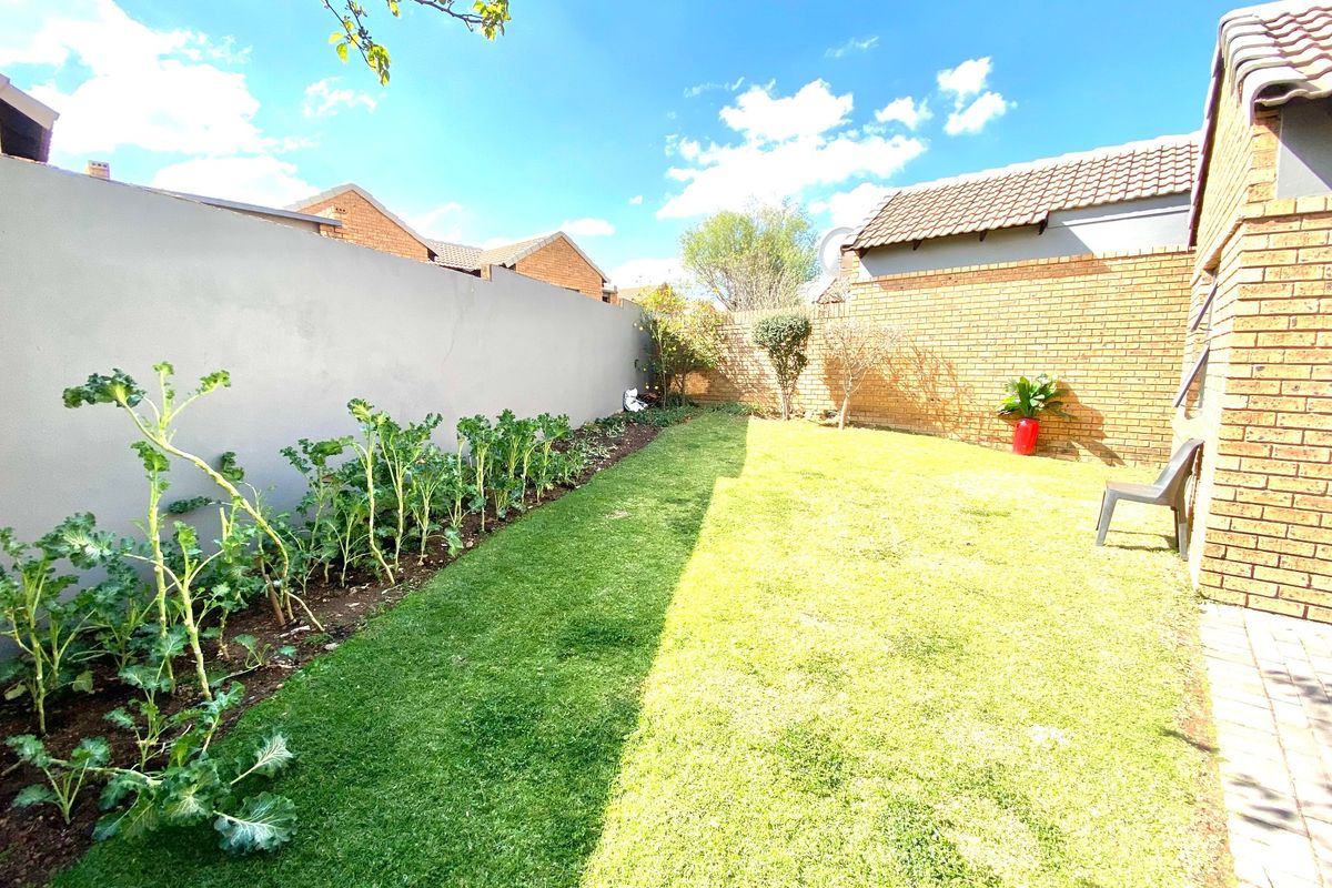 A private rear garden featuring a well-maintained lawn, a brick boundary wall, and a plastered perimeter wall.