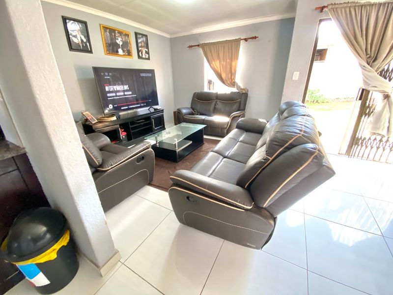 A living room featuring tiled flooring and a sliding door with a security gate, providing access to the exterior.