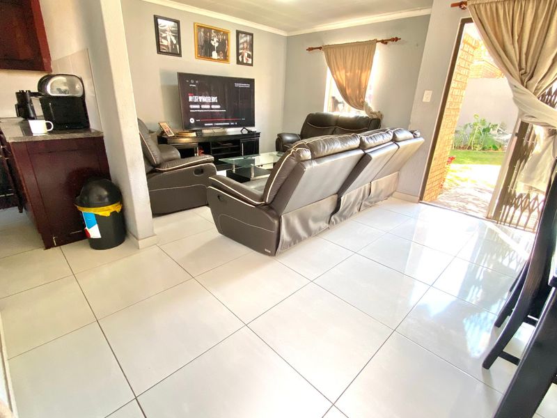 Open plan living area featuring polished floor tiles, neutral wall tones, and direct access to the rear garden through a sliding door.