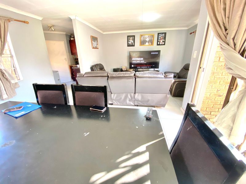 Open plan living and dining area featuring tiled flooring and coved cornicing, with an adjacent view into the kitchen area.