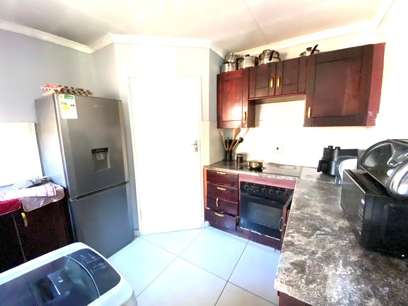 A functional kitchen featuring dark wood cabinetry, laminate countertops, and built-in cooking appliances with tiled flooring.