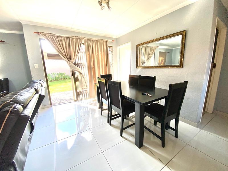 Dining area featuring white tiled flooring, cove cornicing, and a sliding glass door providing direct access to the rear garden.