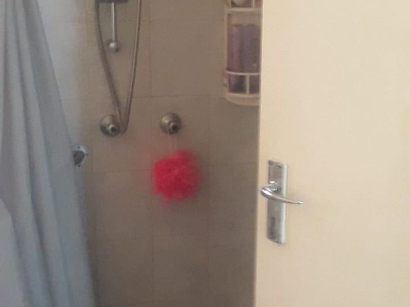 A functional shower enclosure featuring tiled walls and a standard shower mixer setup.