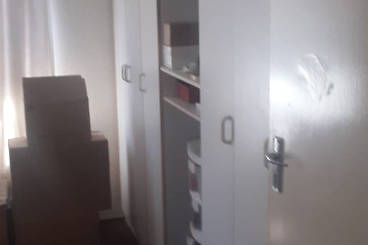A bedroom featuring built-in cupboards with white doors, showing signs of wear and surface scuffing.