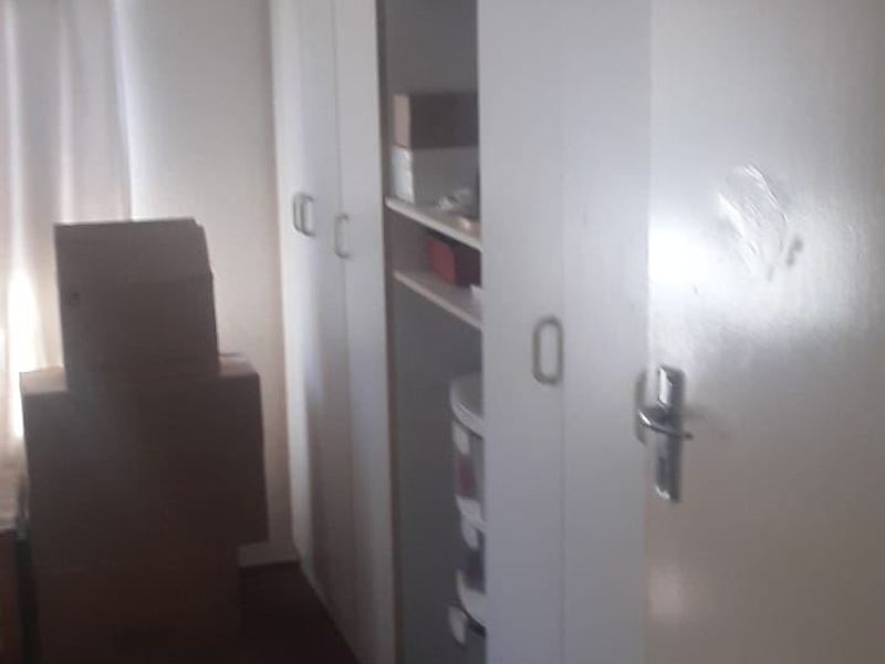 A bedroom featuring built-in cupboards with white doors, showing signs of wear and surface scuffing.
