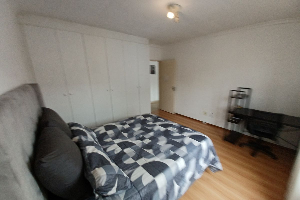 A bedroom featuring laminate flooring and extensive built-in cupboard storage, providing a functional and neutral space.