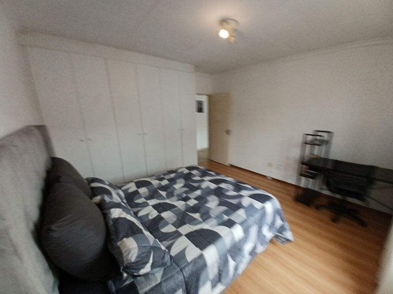 A bedroom featuring laminate flooring and extensive built-in cupboard storage, providing a functional and neutral space.