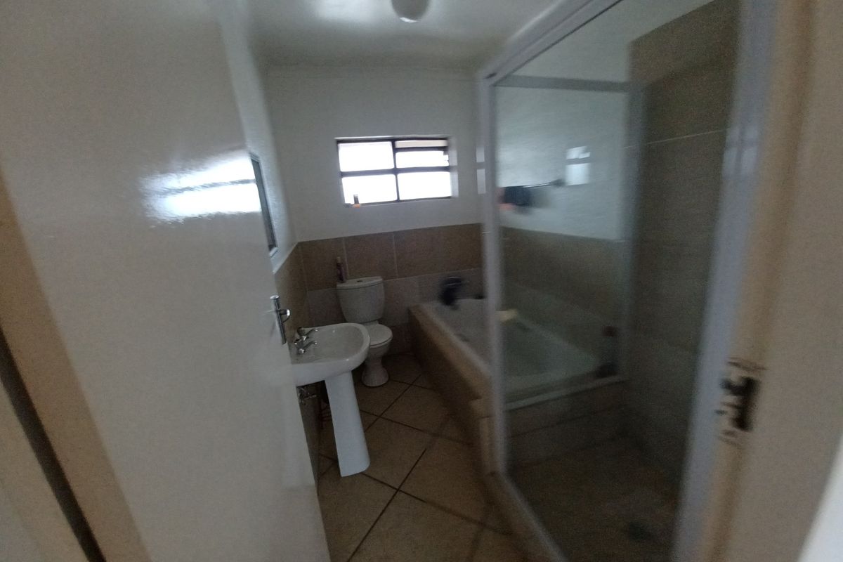 A functional bathroom featuring a pedestal basin, toilet, bathtub, and a separate shower enclosure with tiled finishes.