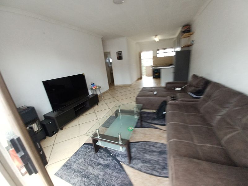 Open-plan living area featuring tiled flooring and a connected kitchen space, providing a functional layout for modern apartment living.