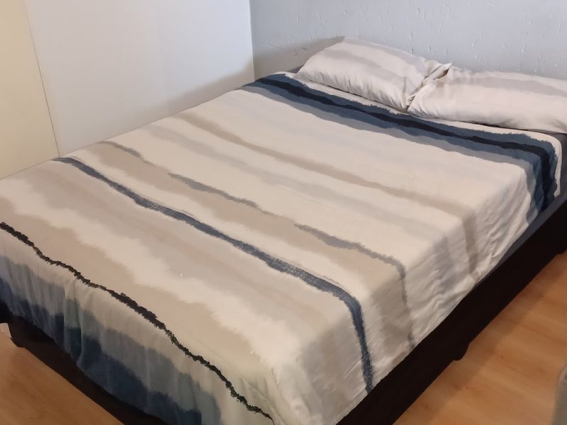 A functional bedroom featuring laminate flooring and a built-in cupboard, providing essential storage space.
