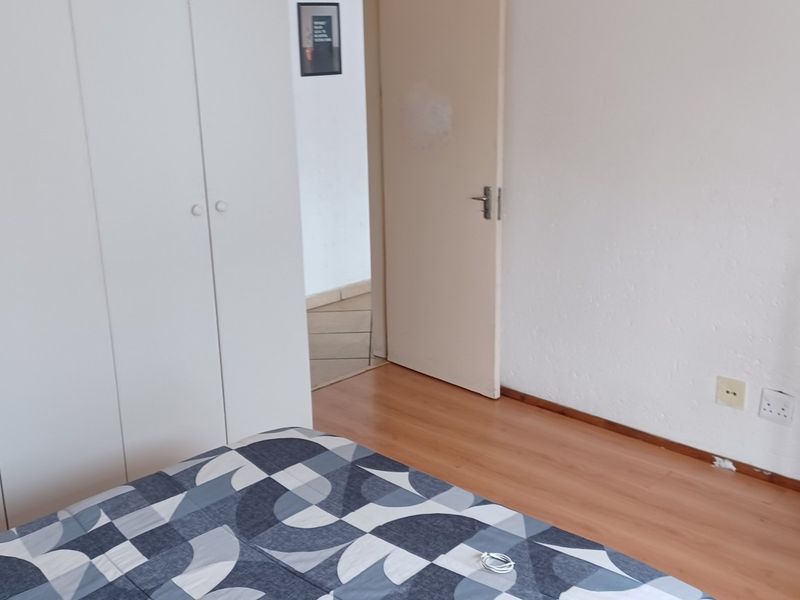 A bedroom featuring laminate flooring and a large built-in wardrobe with white cabinetry.