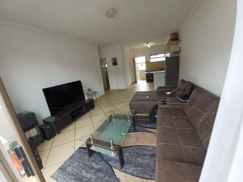 Open-plan living area featuring tiled flooring and a connected kitchen space, offering a functional layout for daily living.