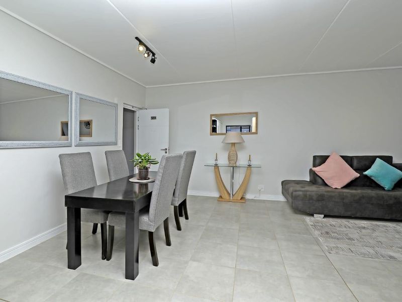 An open-plan living and dining area featuring neutral tiled flooring and modern track lighting, providing a versatile space for relaxation and meals.