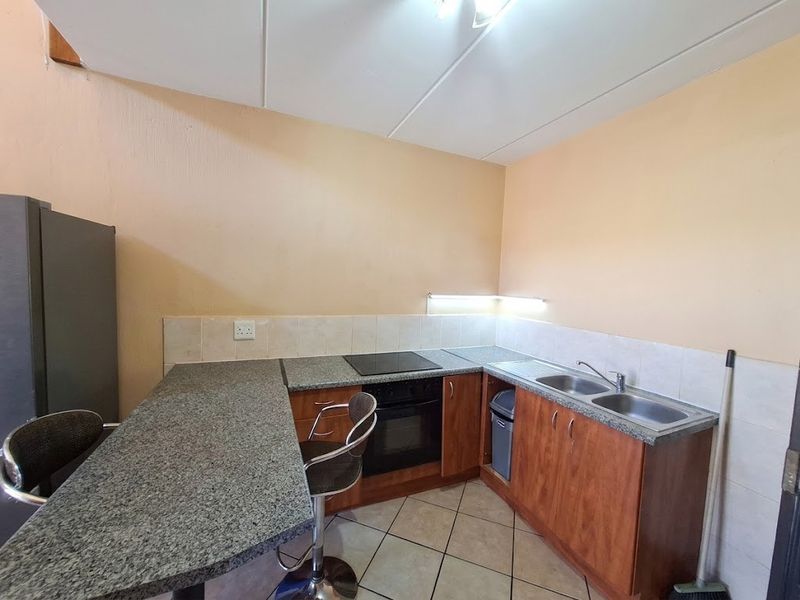 A functional kitchen featuring granite countertops, built-in oven and hob, double bowl sink, and tiled splashbacks with ample cabinetry storage.