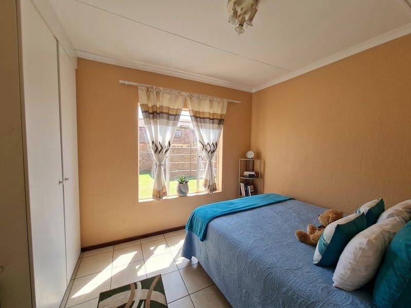A bedroom featuring tiled flooring, built-in cupboards, and natural light from a window overlooking the exterior.