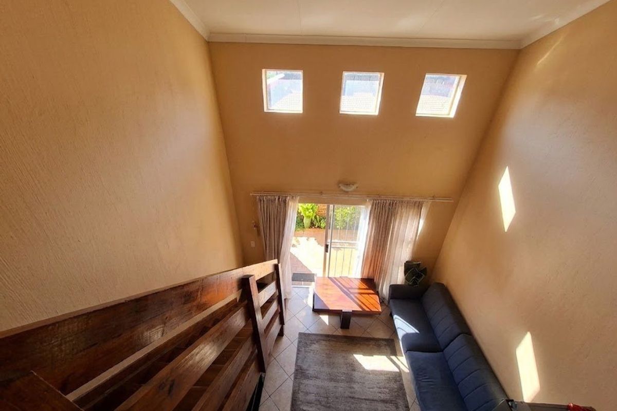 Spacious living area featuring high vaulted ceilings, clerestory windows for natural light, and direct access to an outdoor patio through sliding glass doors.