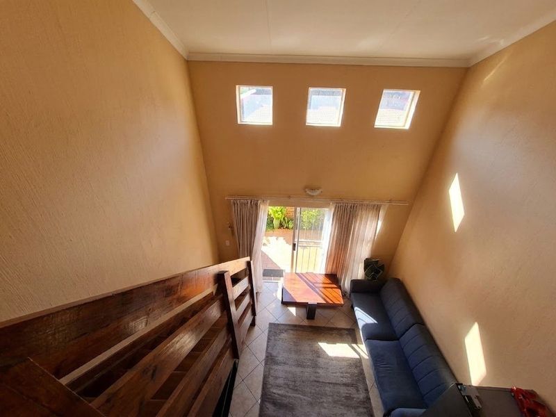 Spacious living area featuring high vaulted ceilings, clerestory windows for natural light, and direct access to an outdoor patio through sliding glass doors.
