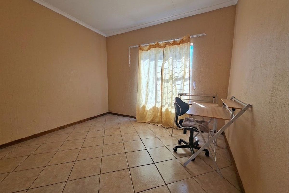 A simple bedroom featuring neutral wall paint, tiled flooring, and a coved ceiling, providing a functional space ready for personalization.