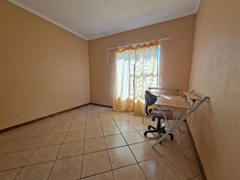 A simple bedroom featuring neutral wall paint, tiled flooring, and a coved ceiling, providing a functional space ready for personalization.