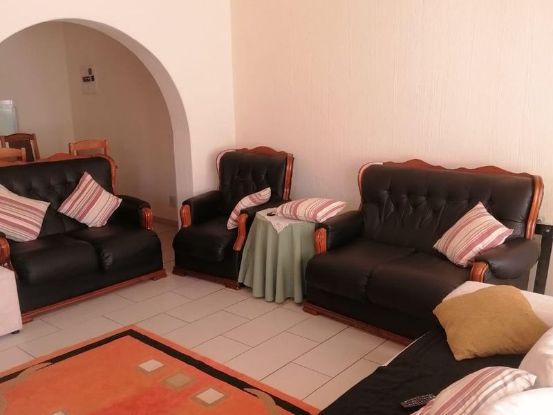 A living room featuring tiled flooring and a distinctive arched doorway leading to an adjacent space.