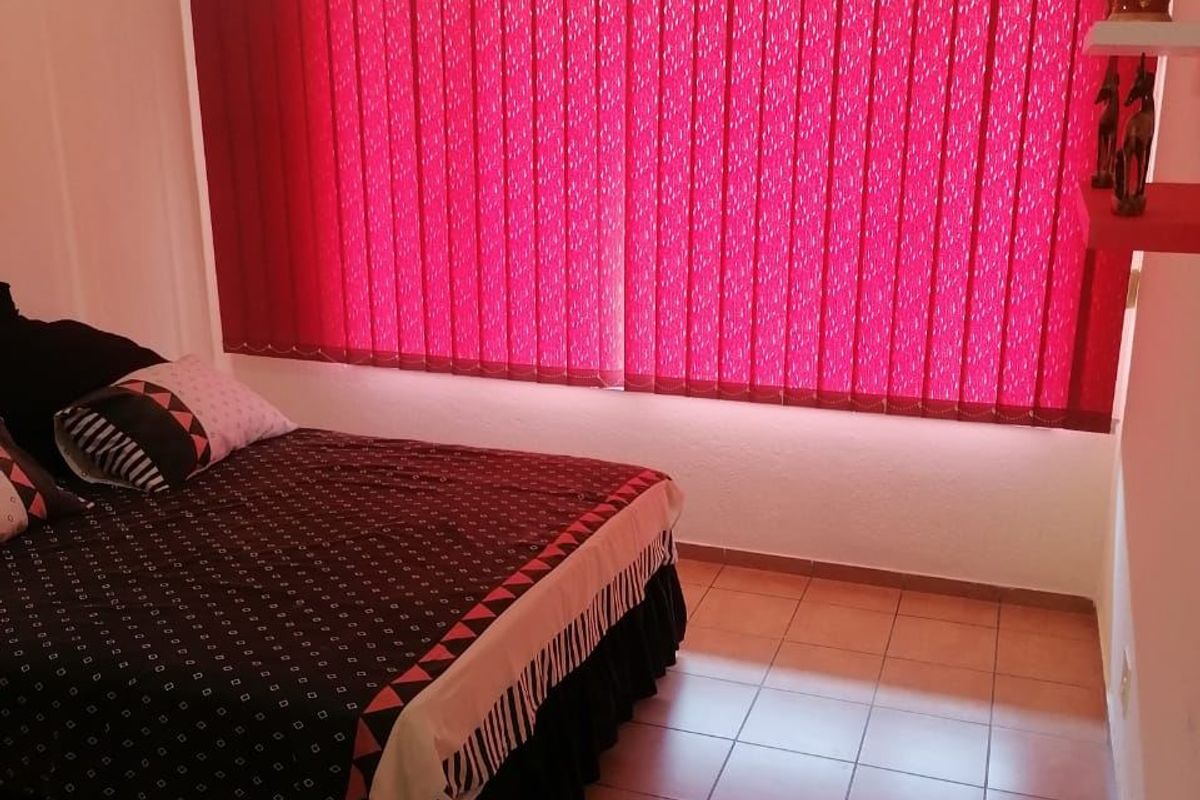 A bedroom featuring tiled flooring, vertical window blinds, and a ceiling light fixture.
