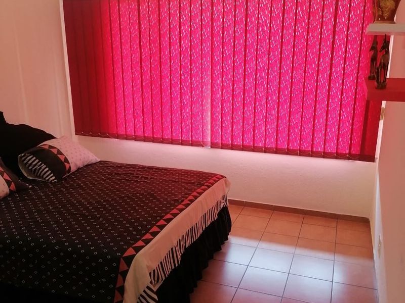 A bedroom featuring tiled flooring, vertical window blinds, and a ceiling light fixture.