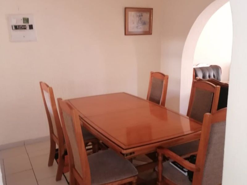 A dining area featuring tiled flooring and a distinctive arched entryway, providing a functional space for meals.