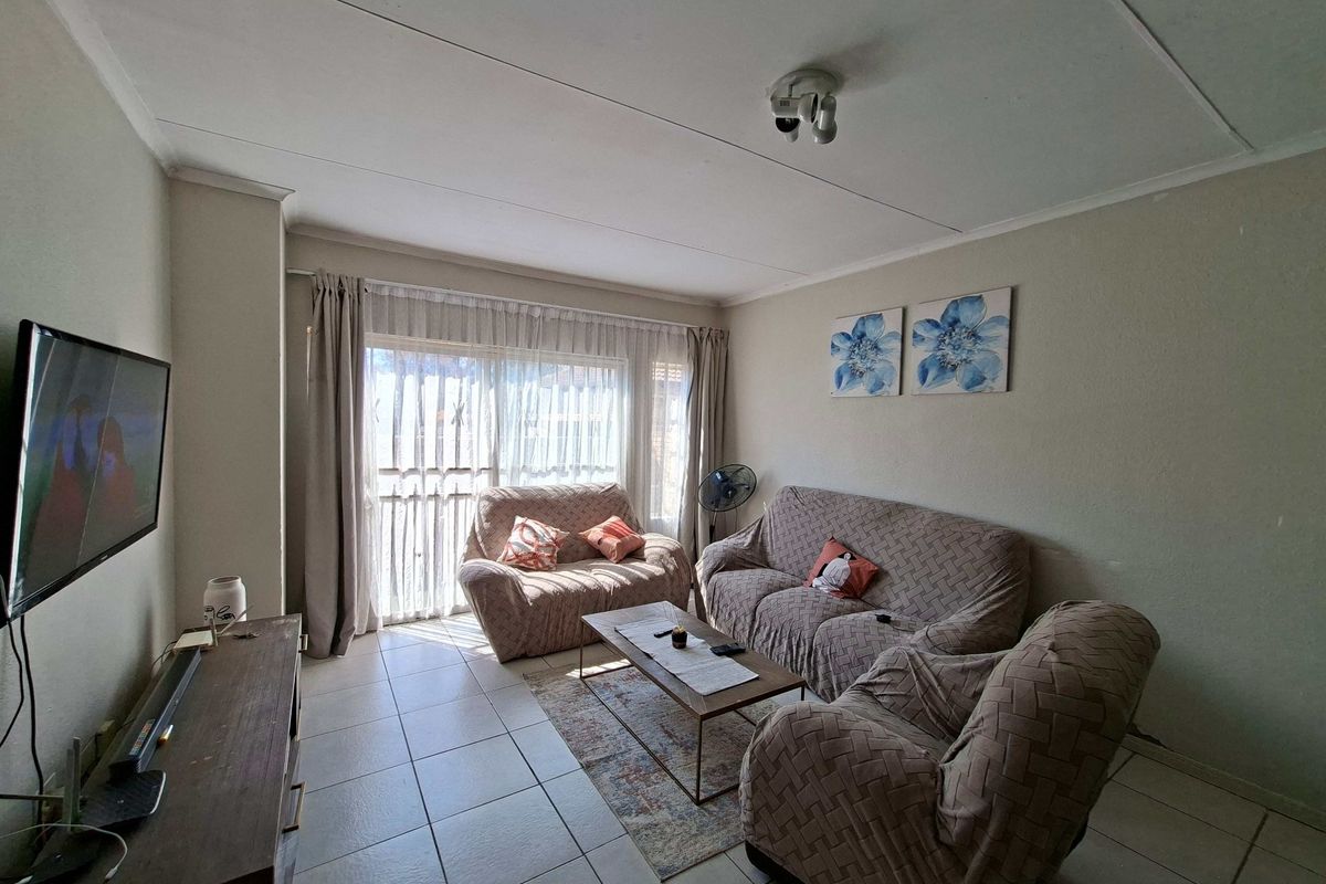 A comfortable living room featuring tiled flooring and a large sliding glass door that provides natural light.