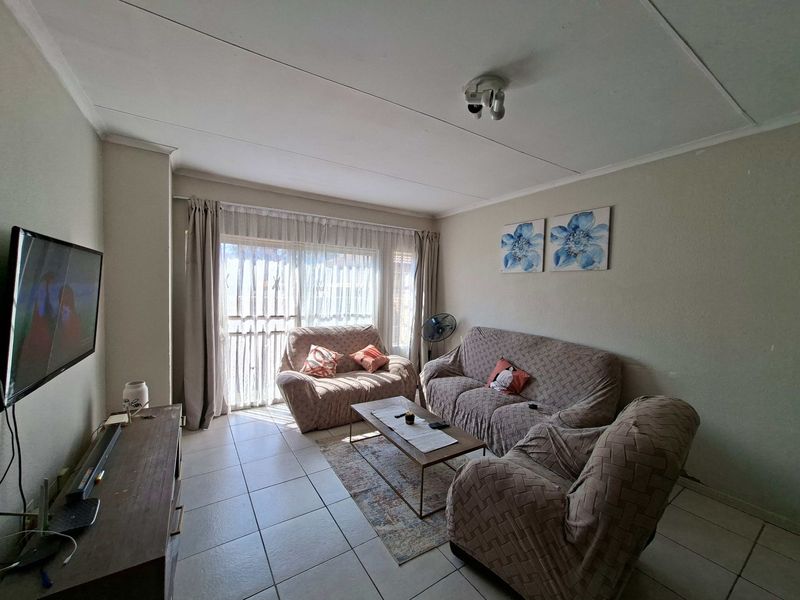 A comfortable living room featuring tiled flooring and a large sliding glass door that provides natural light.