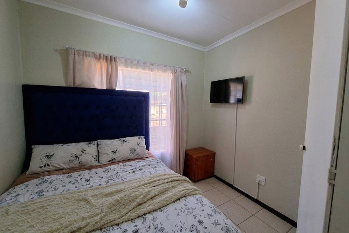 A functional bedroom featuring tiled flooring, neutral wall finishes, and a wall-mounted television point.