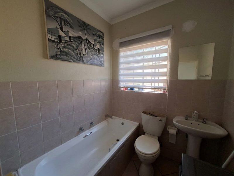A functional bathroom featuring a bathtub, pedestal basin, and toilet, requiring minor cosmetic repairs to wall finishes and toilet fixtures.