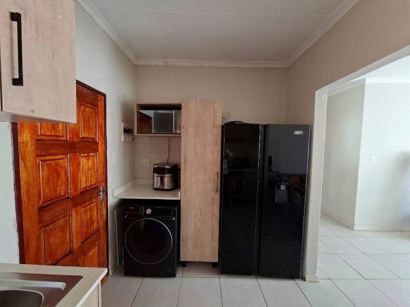 A functional laundry area featuring tiled flooring, built-in cabinetry, and direct access to the interior living space.