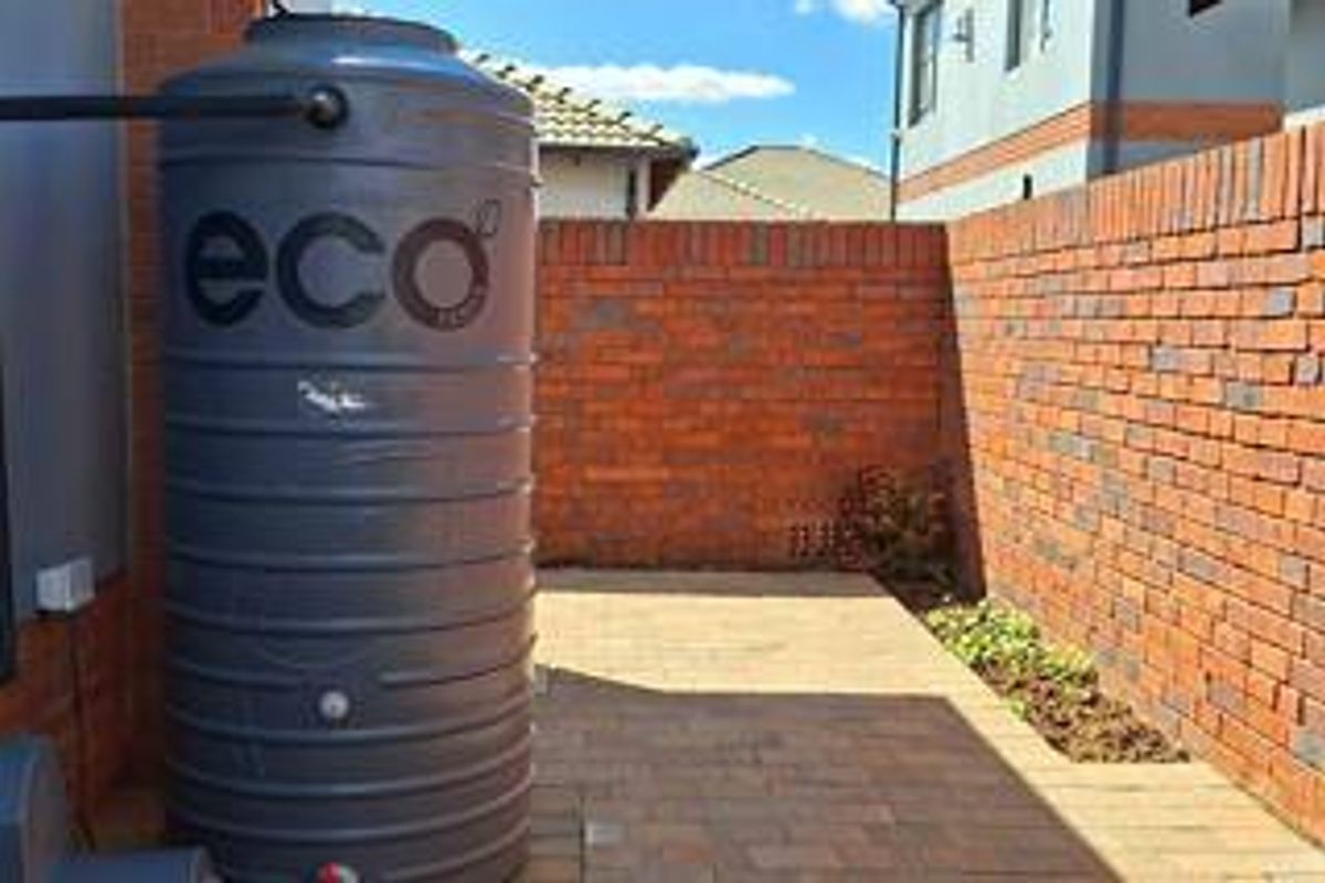 A private rear courtyard featuring a large water tank, paved flooring, and a secure brick boundary wall.