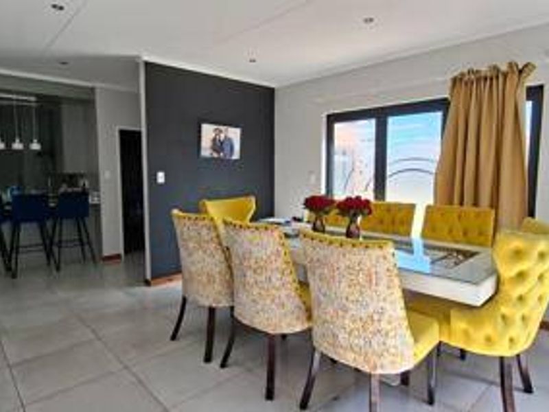 Open-plan dining area featuring tiled flooring, recessed downlights, and a breakfast counter connecting to the kitchen space.