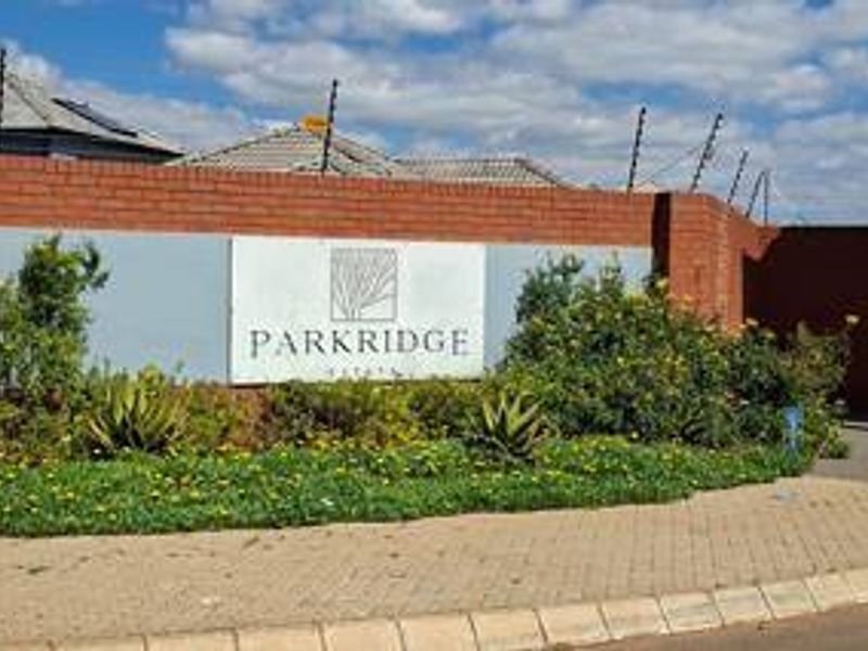 Entrance signage for Parkridge Estate featuring a brick boundary wall with integrated electric fencing and landscaped garden beds.