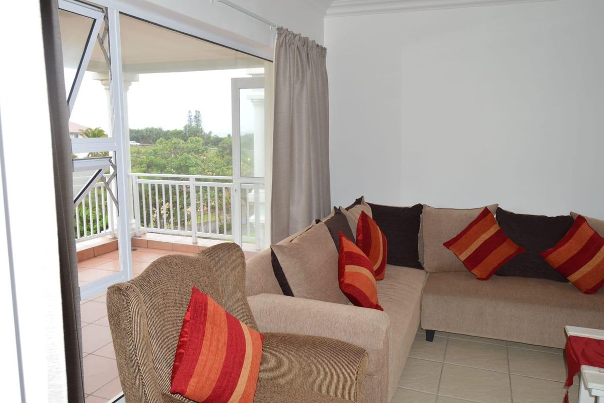 A living room featuring tiled flooring and a large sliding glass door providing direct access to an outdoor balcony area.