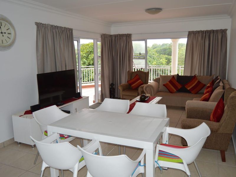 Open-plan living and dining area featuring tiled floors and large sliding glass doors that provide access to a private balcony with garden views.