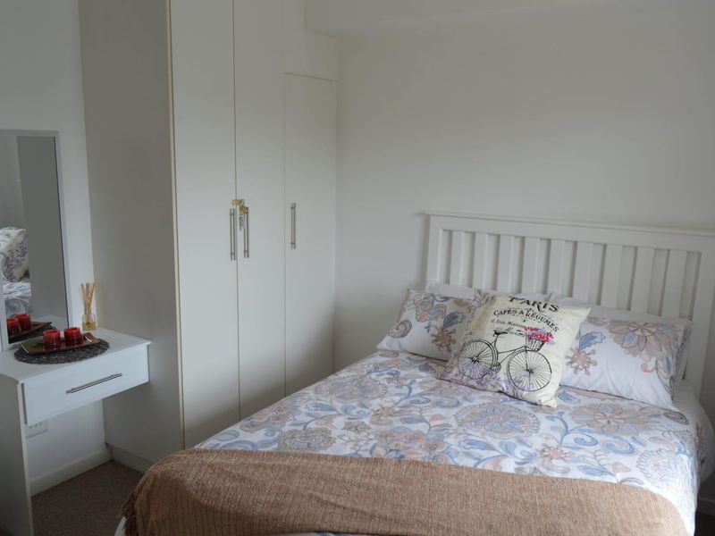 A well-maintained bedroom featuring a built-in wardrobe and a wall-mounted vanity unit, offering a clean and functional living space.