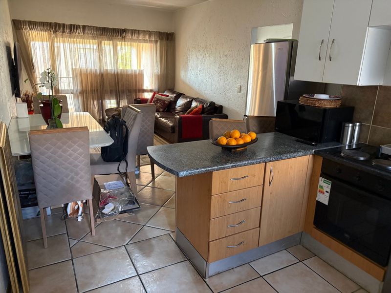 Open-plan living and kitchen area featuring tiled flooring, granite countertops, and direct access to a balcony through sliding doors.