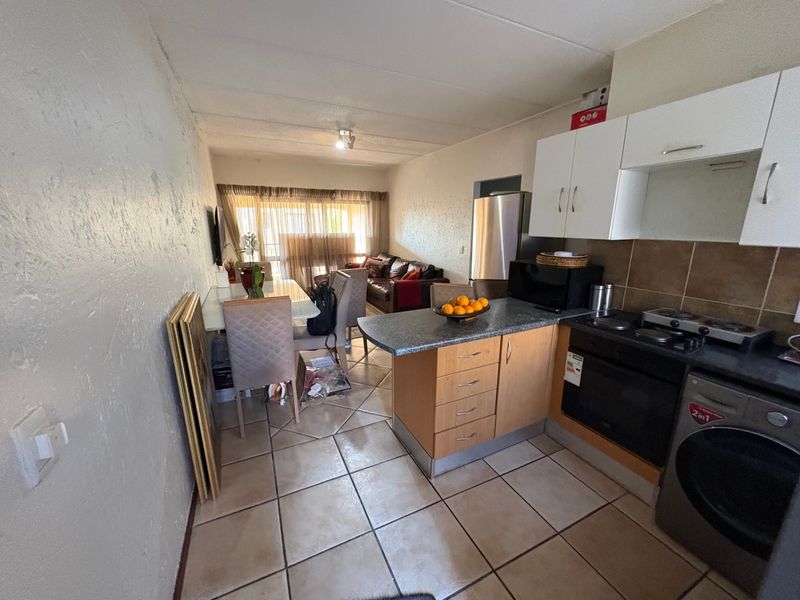 Open-plan living and kitchen area featuring tiled flooring, built-in cabinetry, and a functional layout connecting the kitchen to the dining and lounge space.