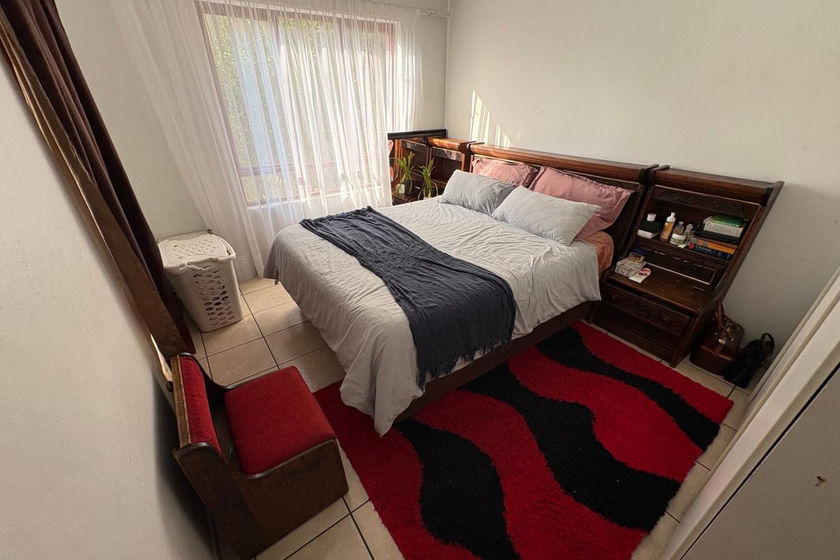 A functional bedroom featuring tiled flooring and a large window that allows for natural light.