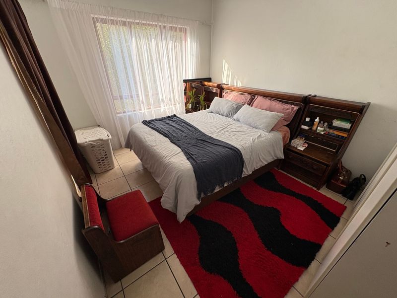 A functional bedroom featuring tiled flooring and a large window that allows for natural light.