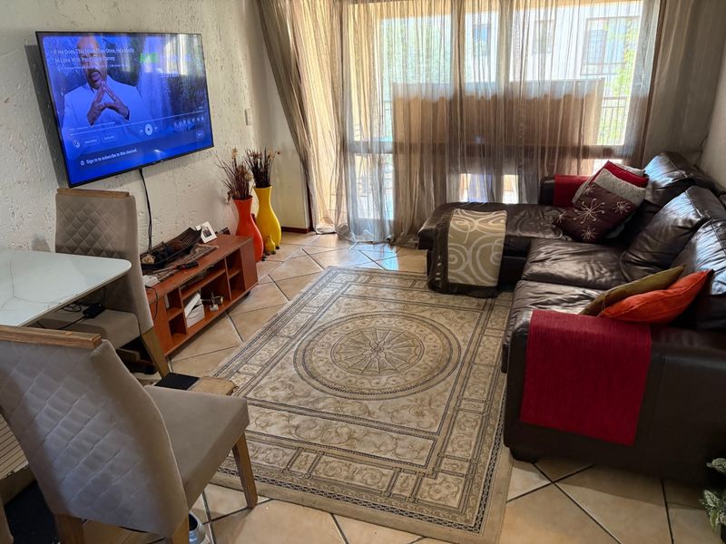 A living room featuring ceramic floor tiles, textured walls, and a large sliding glass door providing natural light and access to the exterior.